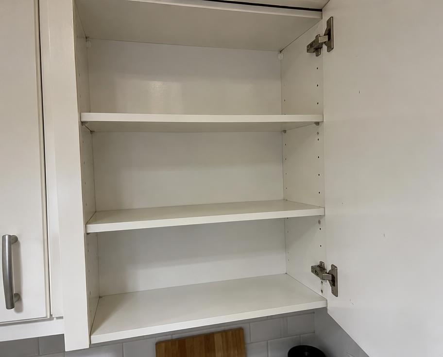 Open, clean, empty white kitchen cupboard